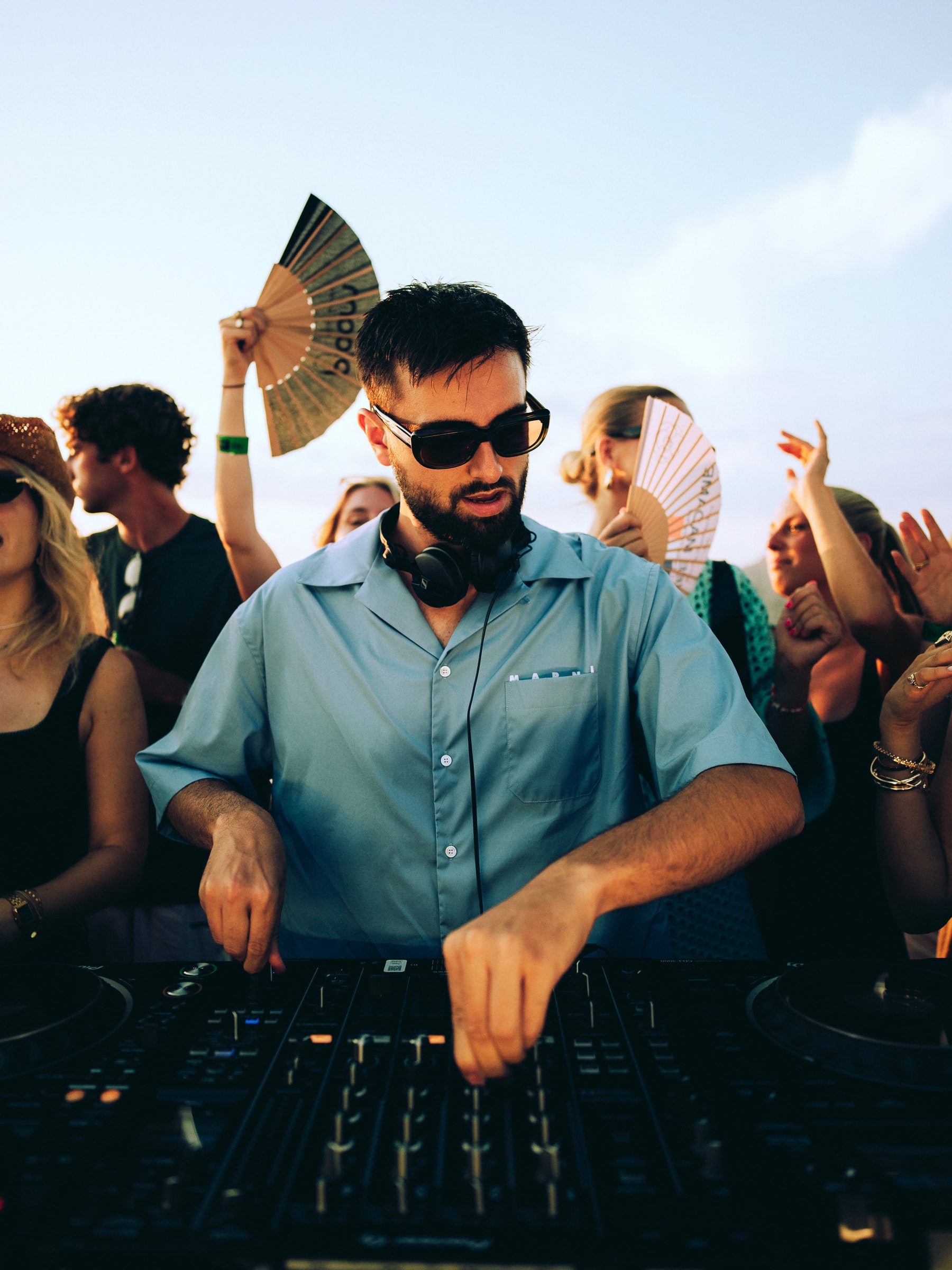GATANO mixing at golden hour, surrounded by dancers holding paper fans.